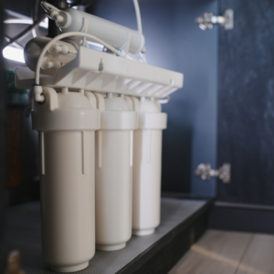 A reverse osmosis water system sits under a sink in a room. 